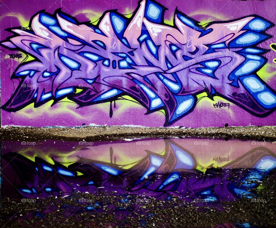 Local street art reflecting in a puddle looks like crystals.