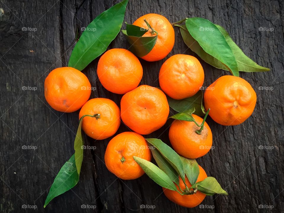 Tangerines with leaves on rustic wooden table