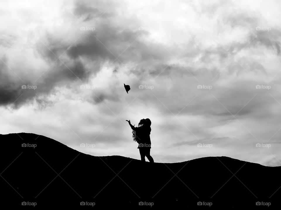 A lady throwing her hat in the sky