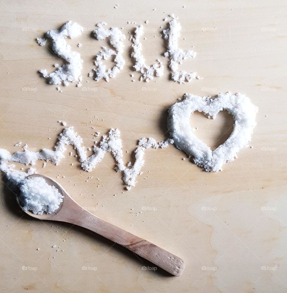 Salt and heart shape against on wooden background, top view