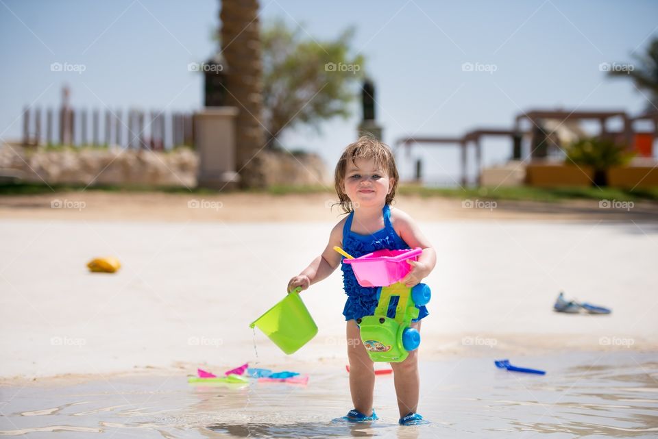 baby girl playing in the pool with water toys