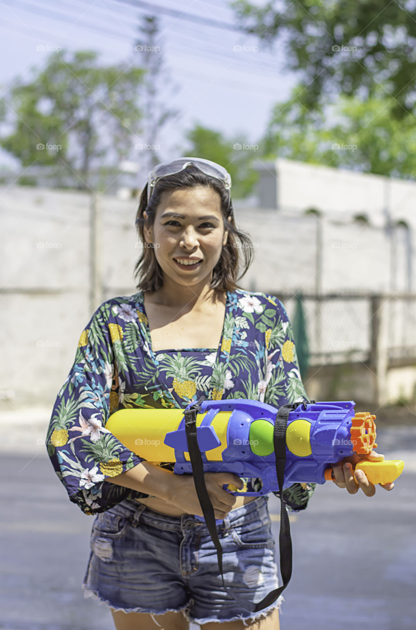 Asian woman holding a water gun play Songkran festival or Thai new year in Thailand.