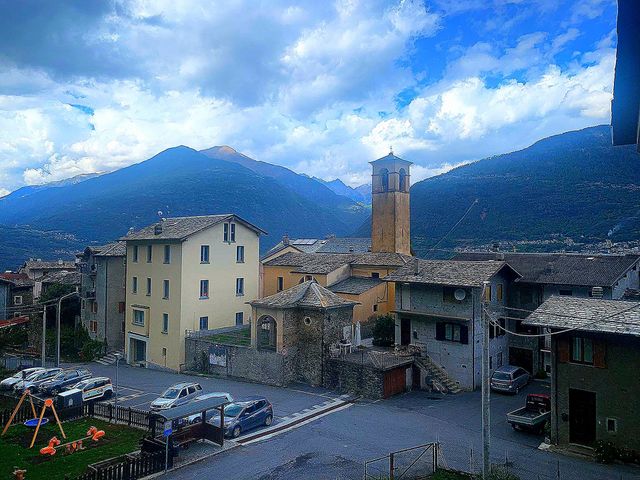 Village.  View of the small settlement of Faedo Valtellino.  Italy.  In the background are the Alps mountains that touch the blue sky with white-gray clouds.