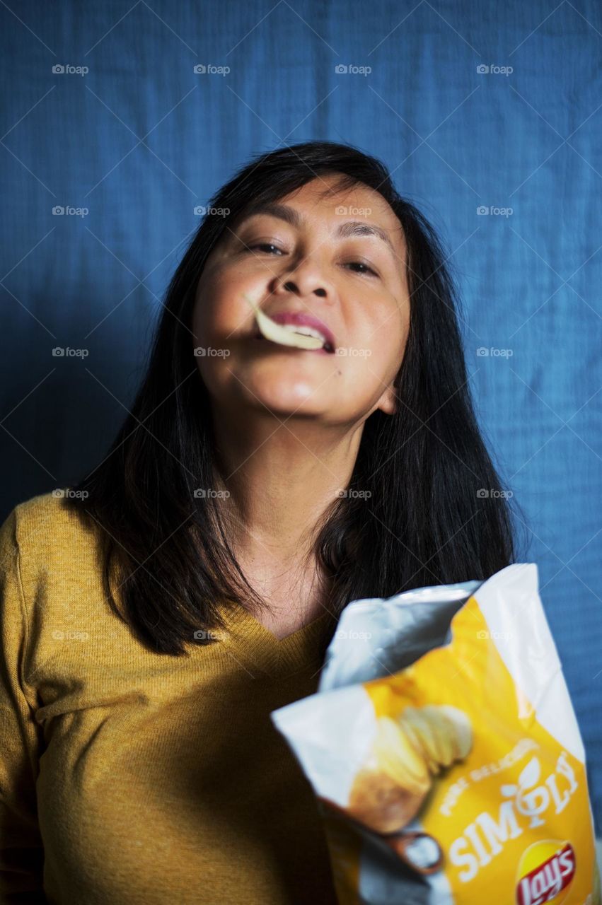 Portrait of a woman eating potato chips 