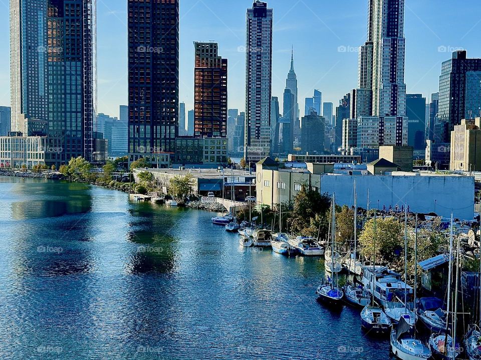 This is “Newtown Creek” seen from the “Pulaski Bridge” that connects “Greenpoint”, Brooklyn to LIC, Queens on an Indian summer day in early November 2023. In the distance “Manhattan” and the “Empire State Building” are visible. Hypnotic Productions