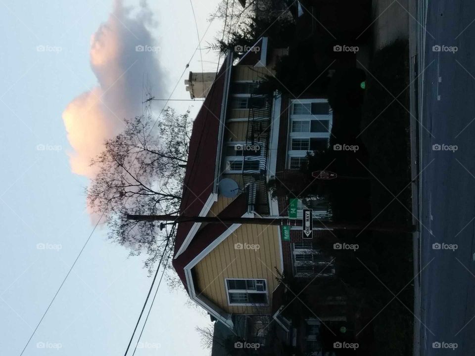 house on a quiet street colorful cloud above at dusk