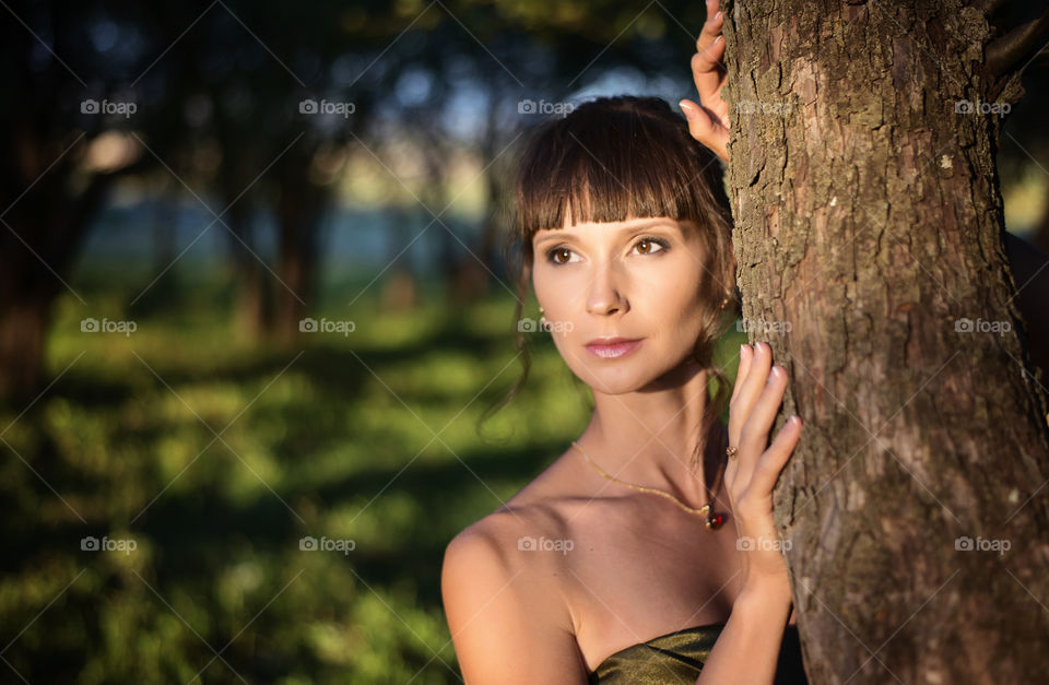 Portrait of beautiful woman posing near the tree