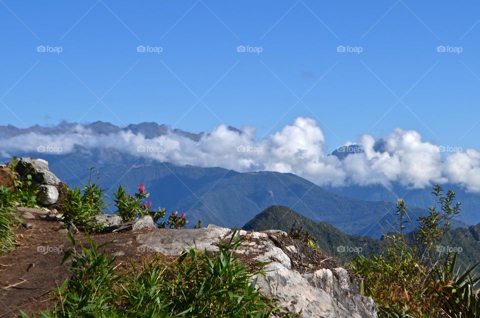 This is what hiking to the top of Machu Picchu mountain looks like, at the eye level with floating clouds among picturesque  nature views of near-by mountains. 