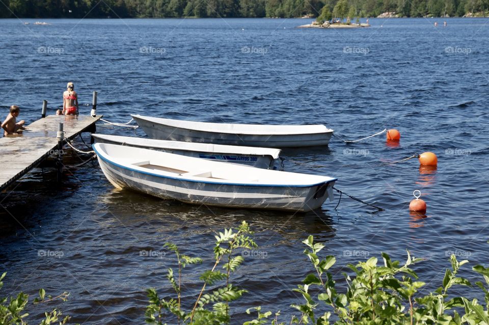 Children on pier enjoying swimming in the lake on a beautiful summer day in June 