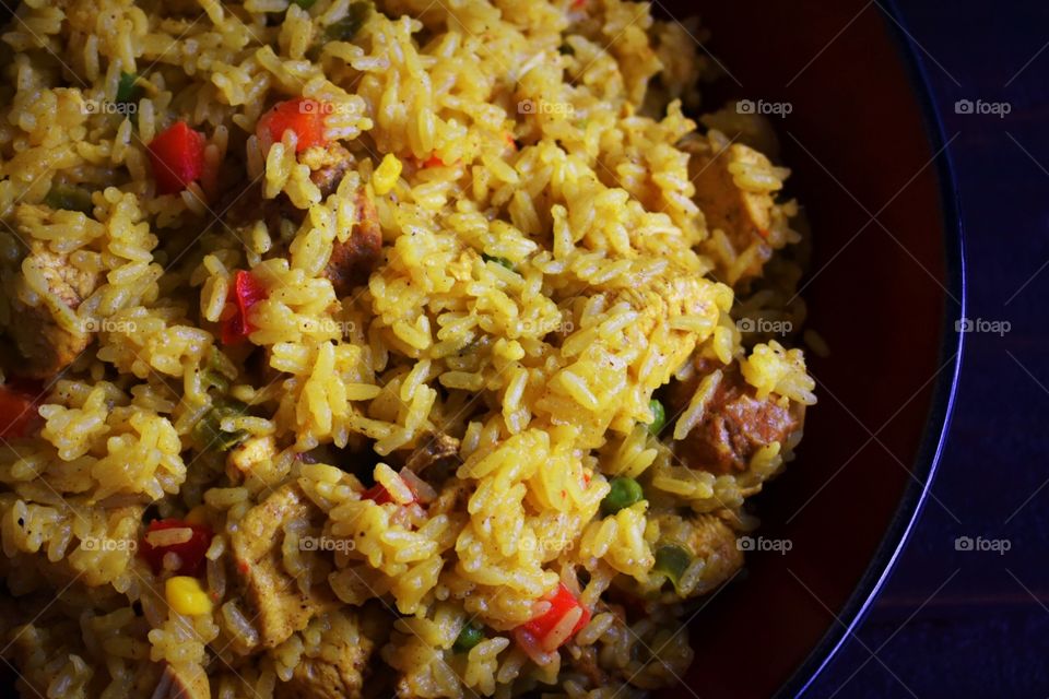 Closeup of a bowl of Cuban yellow rice with chicken, sausage, and vegetables 