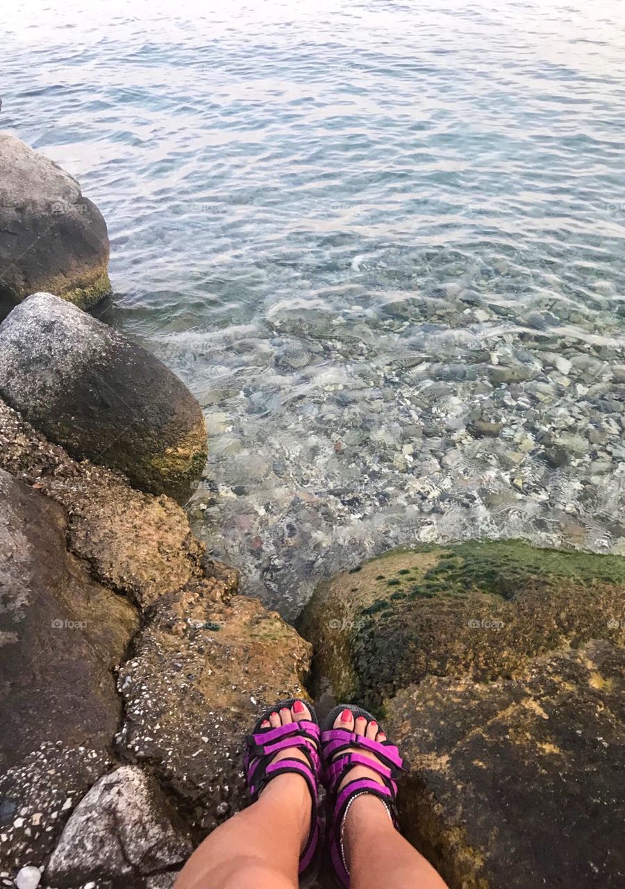 the clear water ,can see the rocks below , my feets are wearing purple shoes and standing on large rocks covered with moss. The water is cool, and the air is great