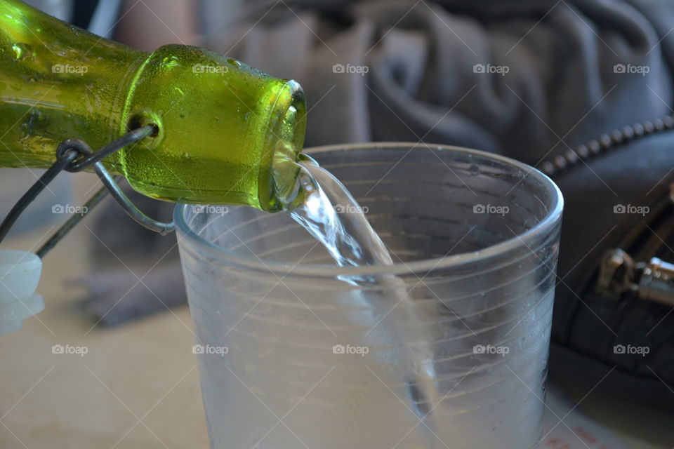 Pouring water from a green glass bottle closeup
