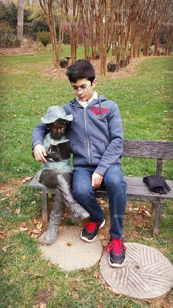 Teenage boy with statue at Gibbs Gardens.