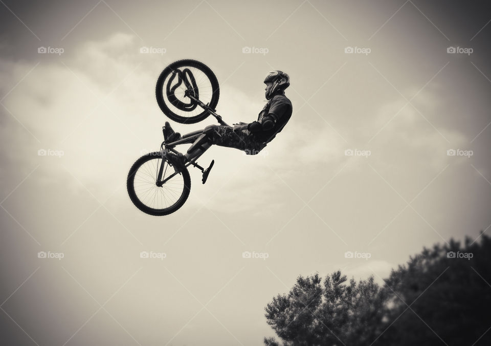 Spring games, bicyclist fly from hill to river, freezing moment at sky, black and white 