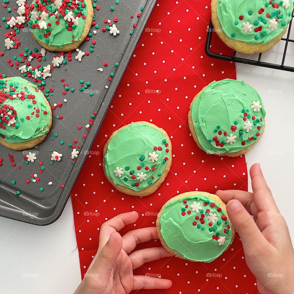 Child reaches for brightly colored cookie, colorful holiday cookies, baking homemade cookies 