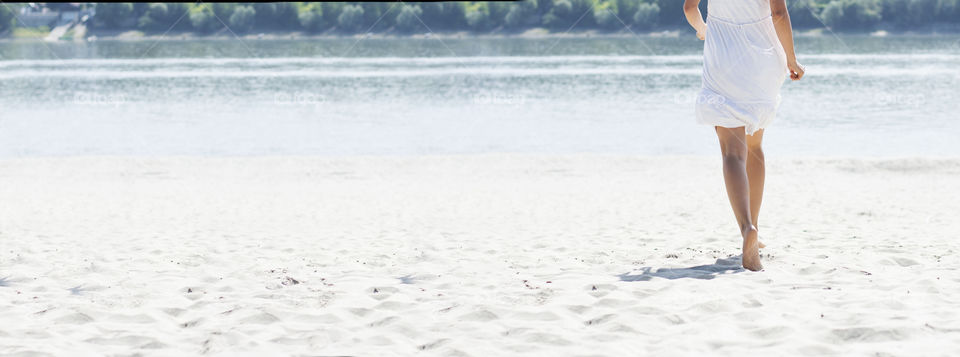 woman running on beach. woman in white dress running across sandy beach