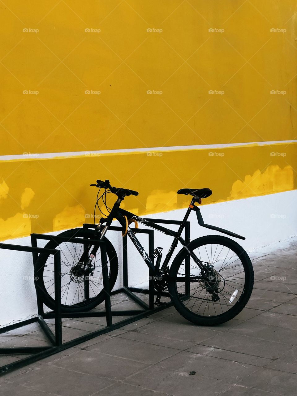 One lonely bicycle near yellow wall 