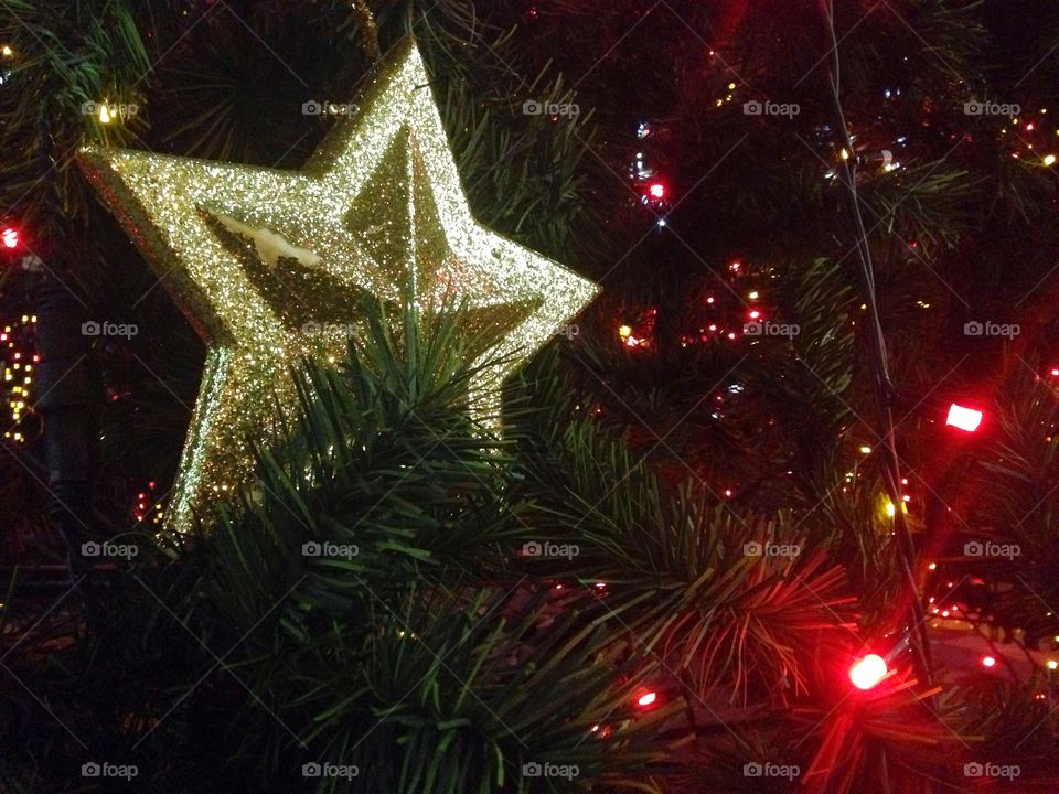 Gold plastic star, balls, red lights garland and other Christmas decorations on artificial fir tree in Moscow, Russia