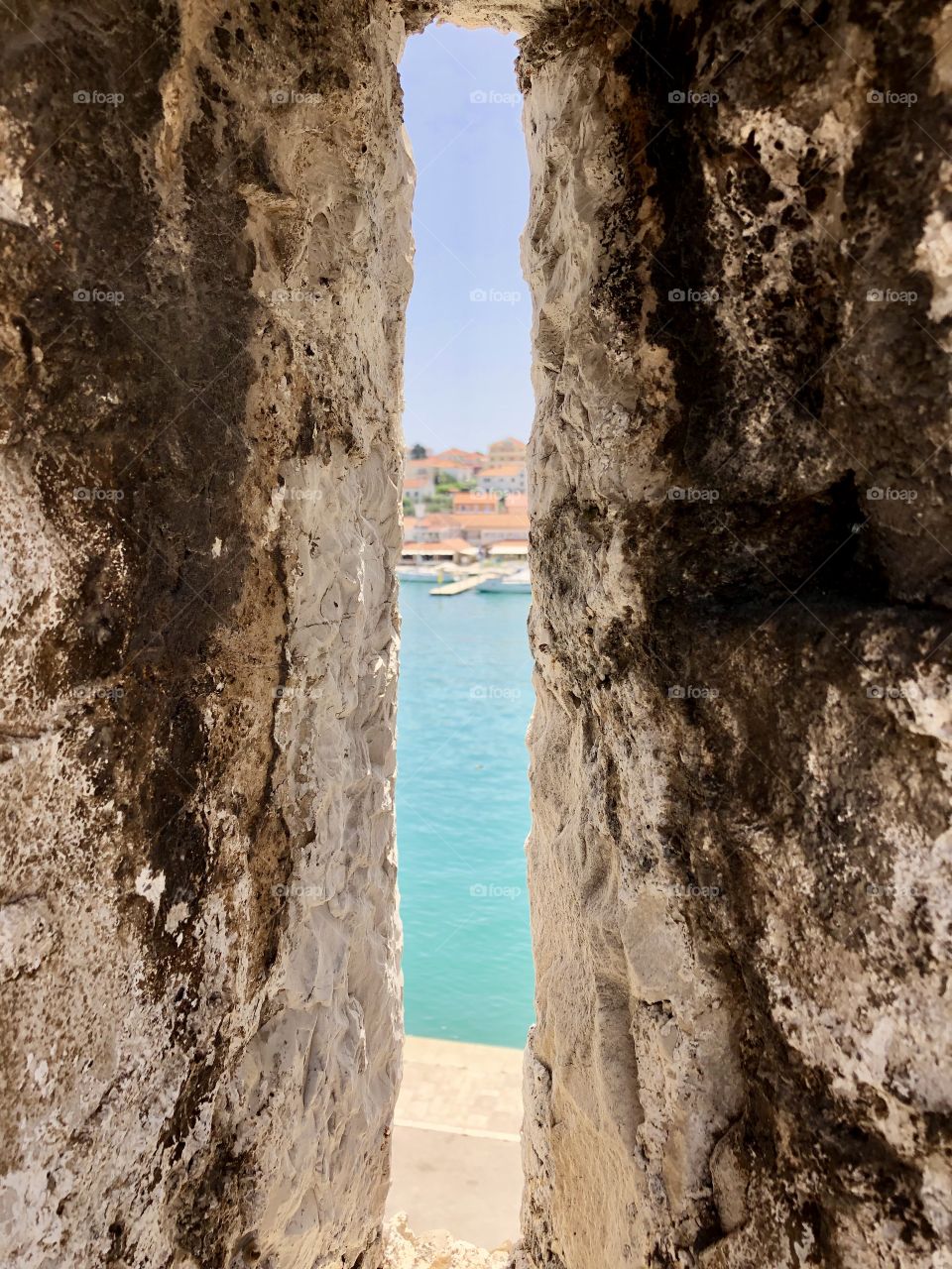 The petit town of Trogir, Croatia through an arrow slit in one of the castles bordering the blue Adriatic Sea
