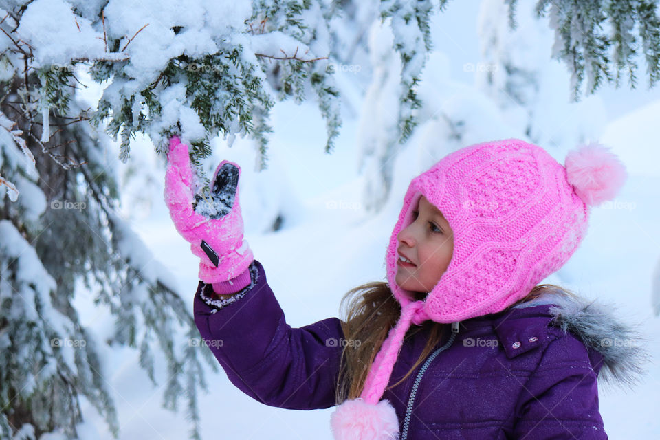 Child admiring the flaky snow on a branch