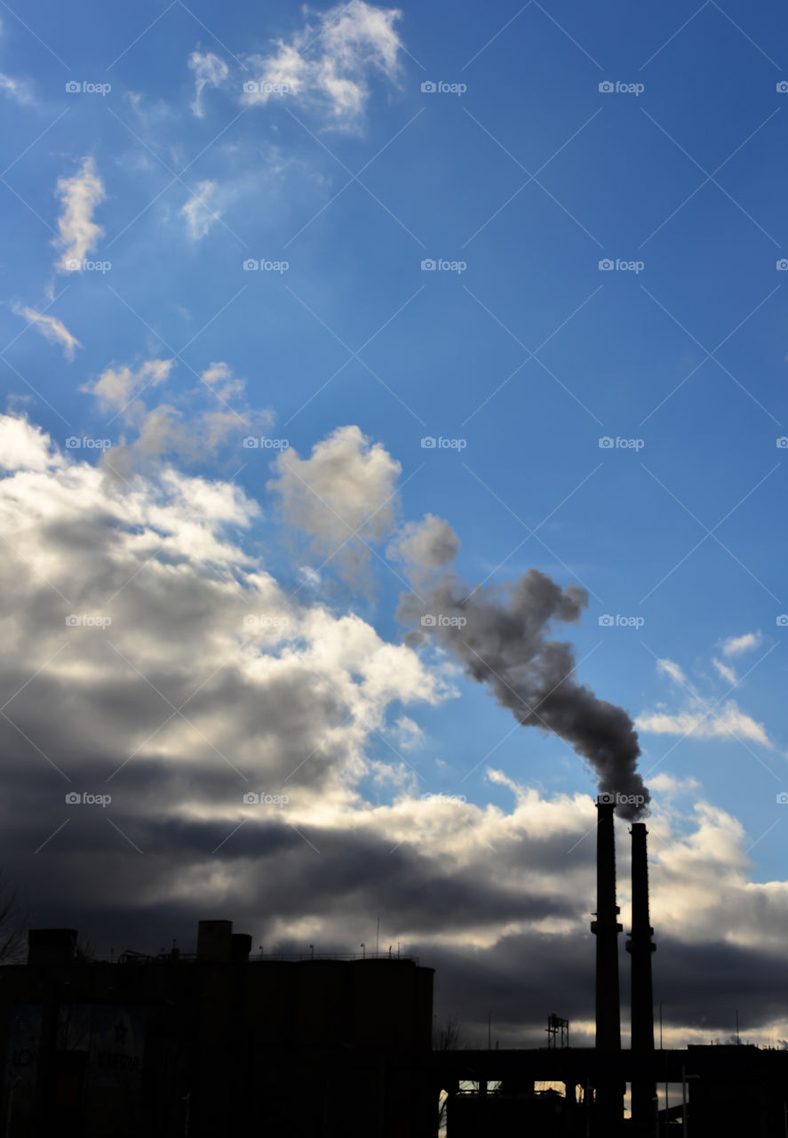 Looking up at smoke stack. Looking up at a smokestack billowing smoke into the blue clouded sky