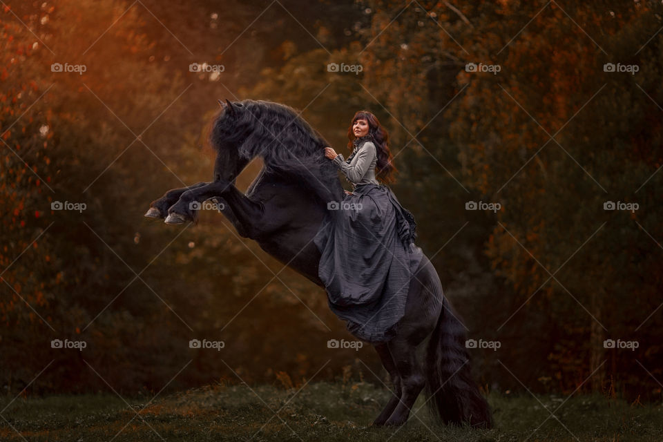 Beautiful young woman on black stallion 