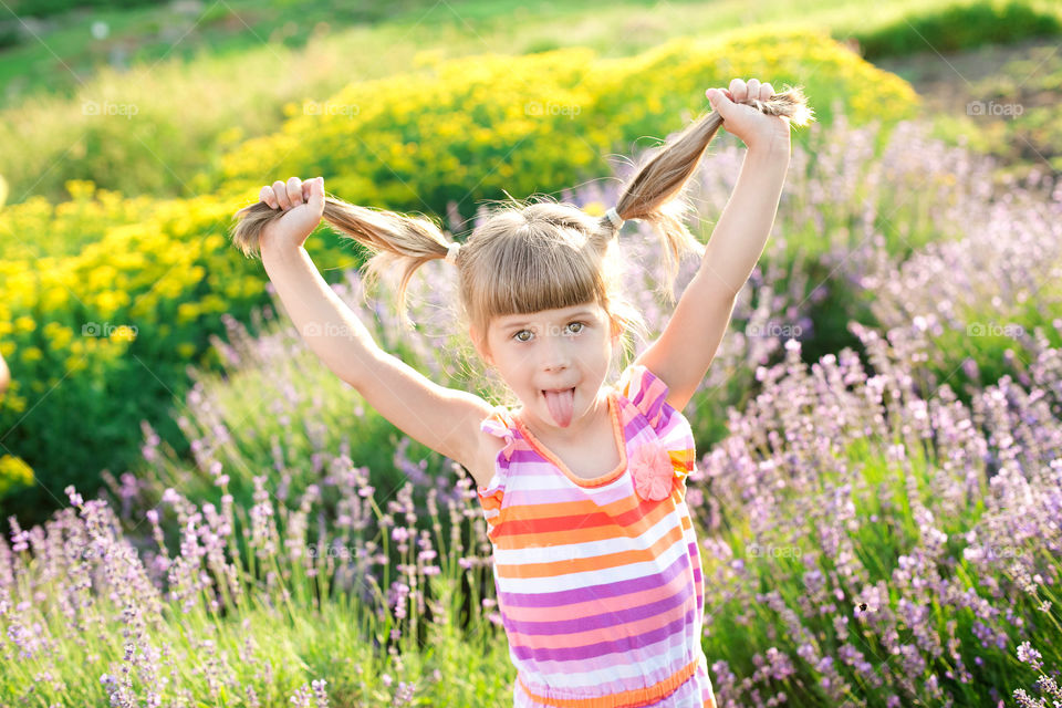 Cute girl holding hair with arm raised in the flower field