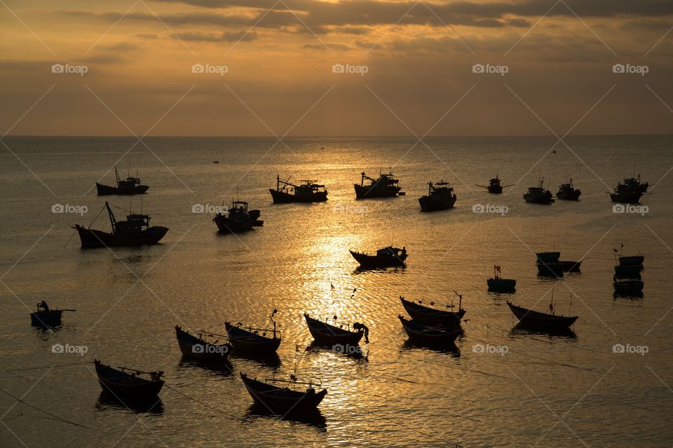 Silhouetted boats sunset. Small fishing boats anchored during sunset. Backlit scene with silhouetted boats. 