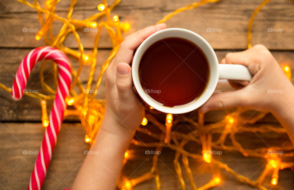 High angle view of child's hand with cup of tea