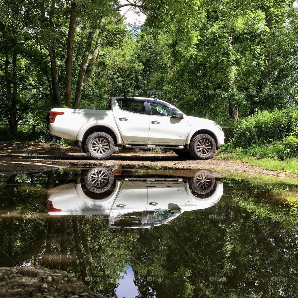 White pick up car parked up next to a large puddle that looks like a lake ! 🤍