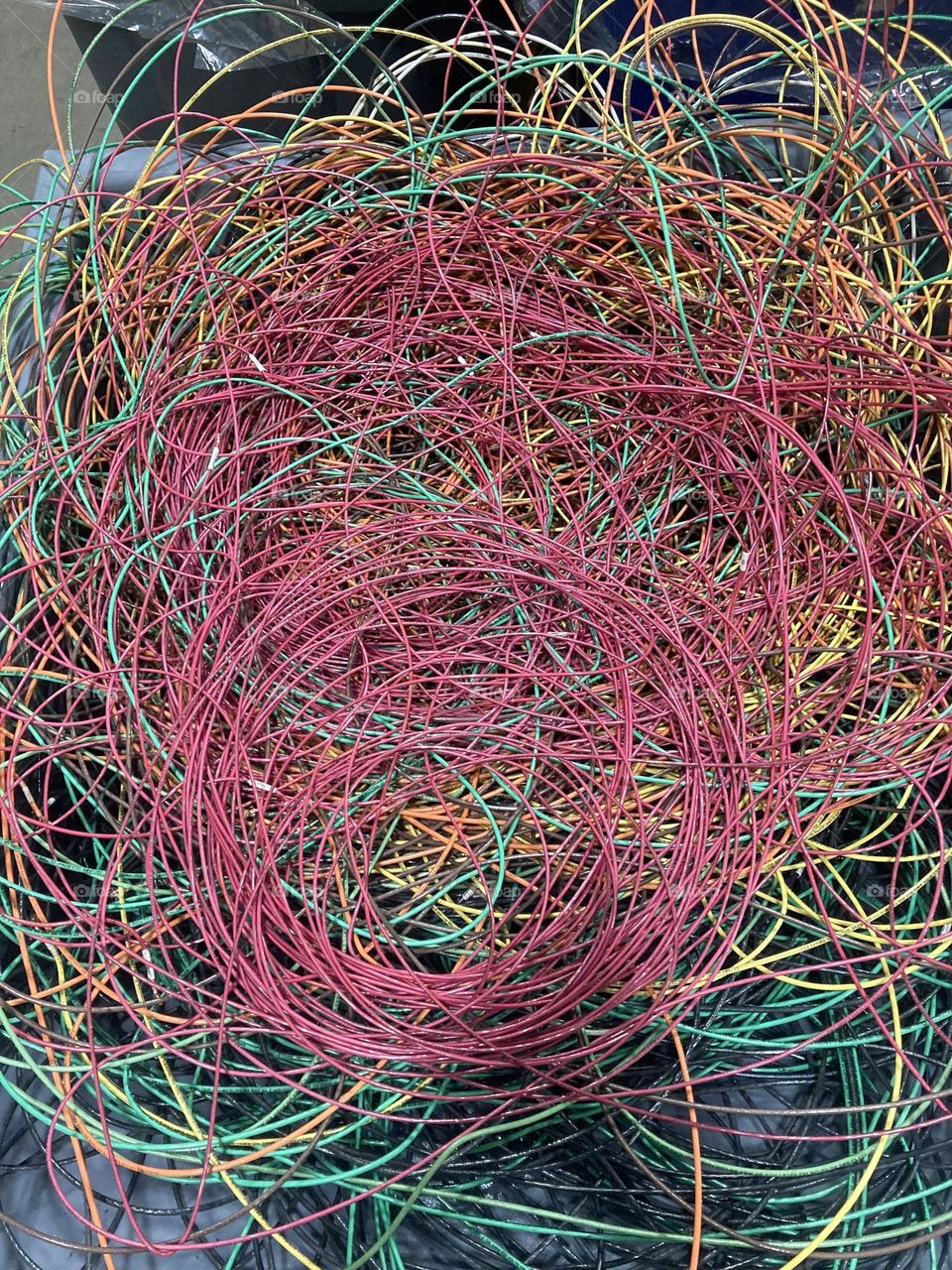 A pile of layered,circular,multi colored scrap wire,discarded after an electrical project. 