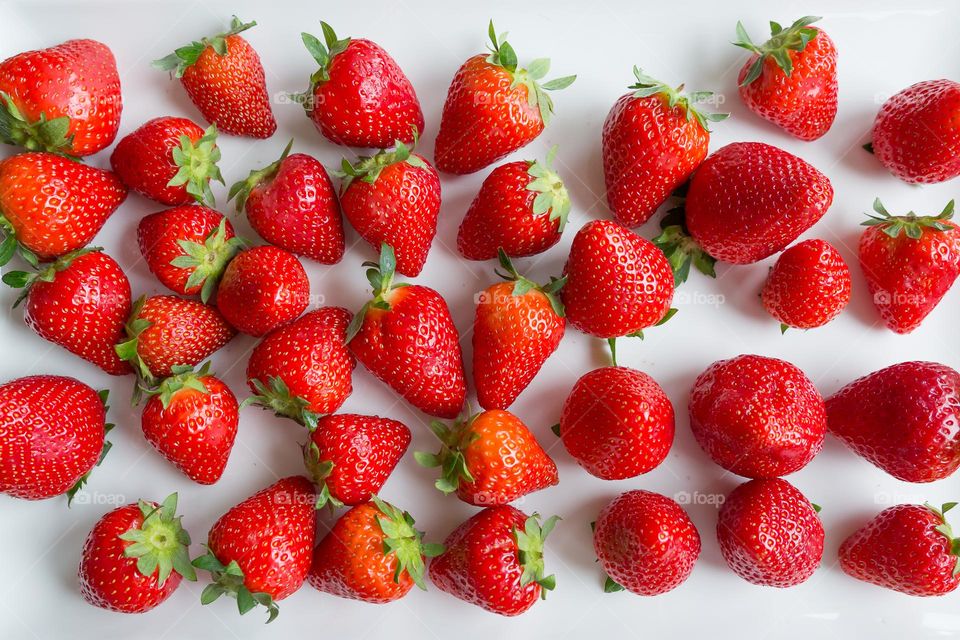 Delicious fresh strawberries lying on a white plate, shot taken from above 