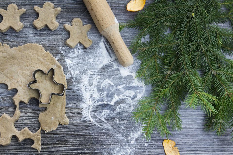 Christmas, gingerbread cookies on a wooden table sprinkled with flour, with tangerines and a green Christmas tree.