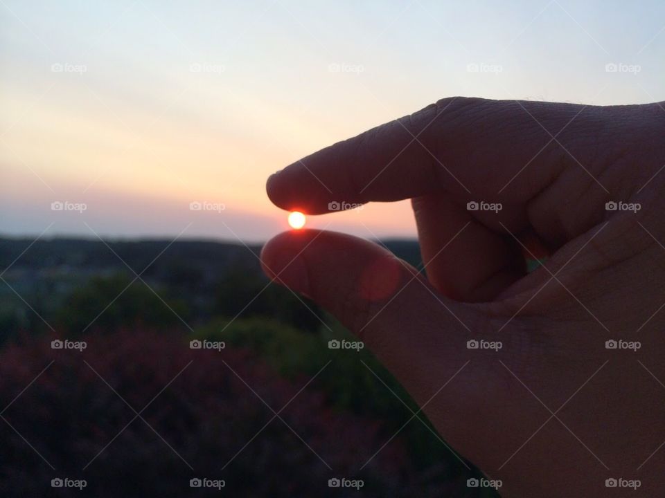 Holding the sun . Creating a optical illusion. 