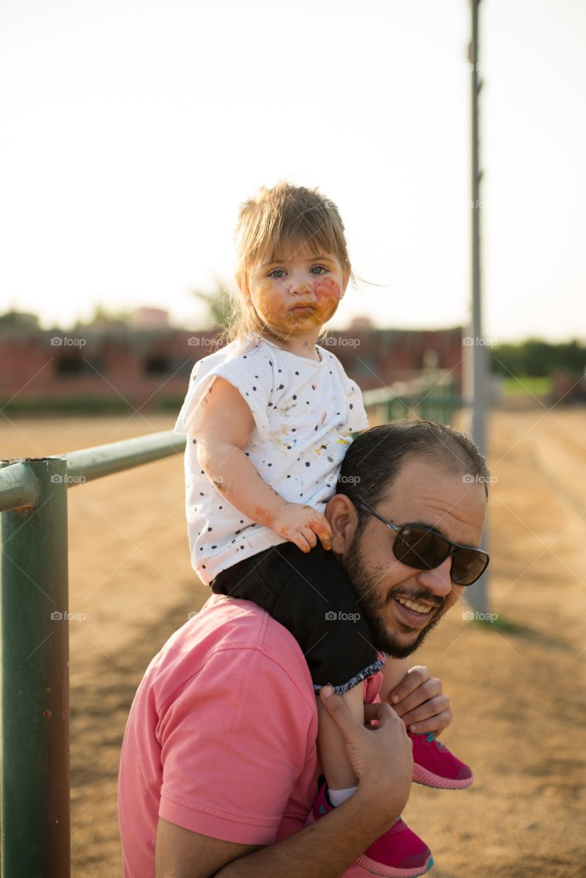 dad carrying his daughter on his neck