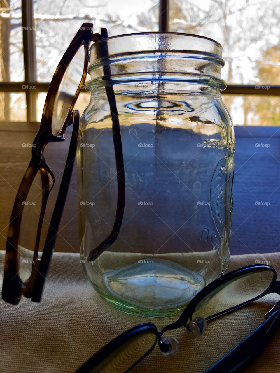 Eye glasses, mason jar and desk by window 