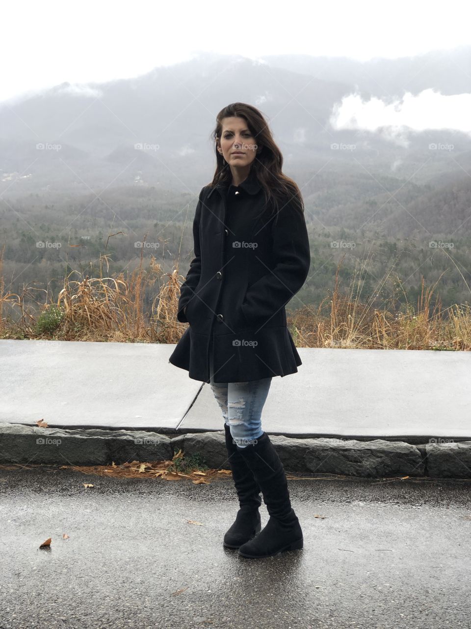 Petite brunette woman in a serious pose in the mountains 
