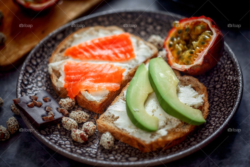 Dietary sandwiches of grain toasts with cream cheese, fish, avocado and passion fruit 