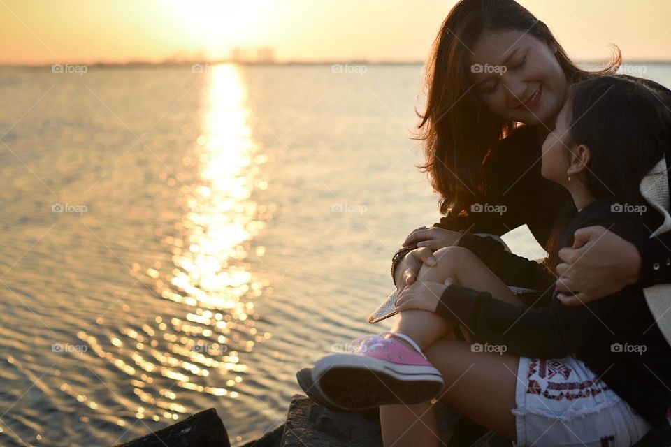 Mother and daughter enjoy the sunset at beach