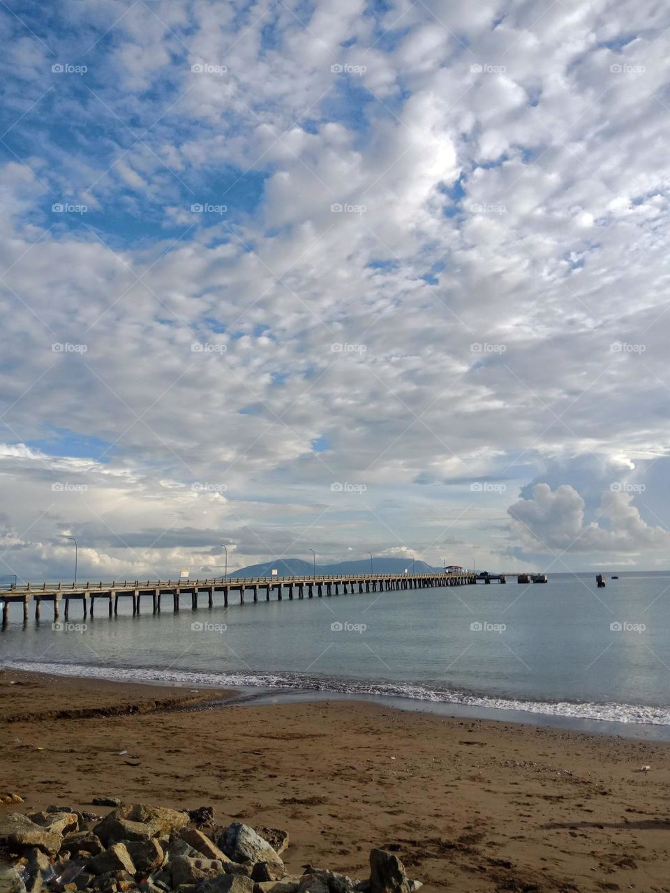 An afternoon with clouds. Atauro island at the horizon, a pier for fuel boats and beach