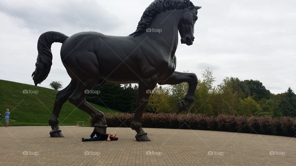 Large horse sculpture crushing a man