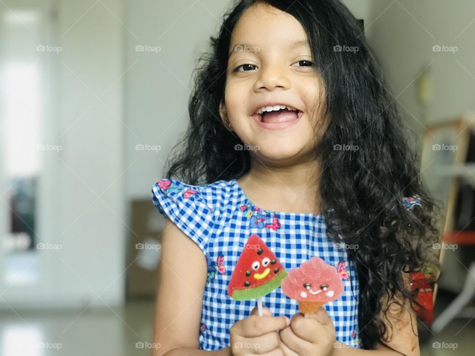 Four years old girl holding two candy lollipops and smiling .she looks very pretty.