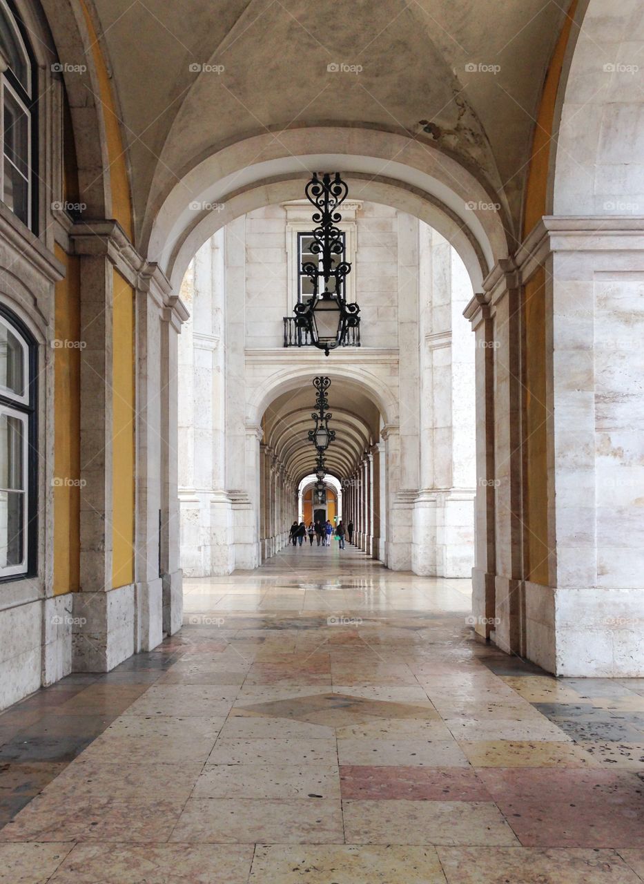 A typical working day at Terreiro do Paço, also known as Praça do Comércio. People crossing the square under the marble arches to avoid the rain.