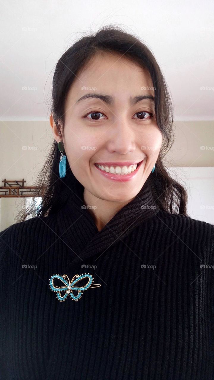 Smiling woman with butterfly pin on her dress 