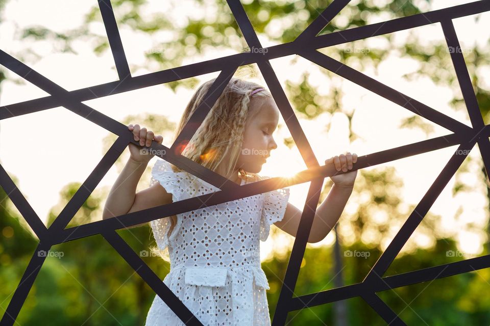 Lifestyle portrait of beautiful little Caucasian girl with blonde hair outdoor on sunset 