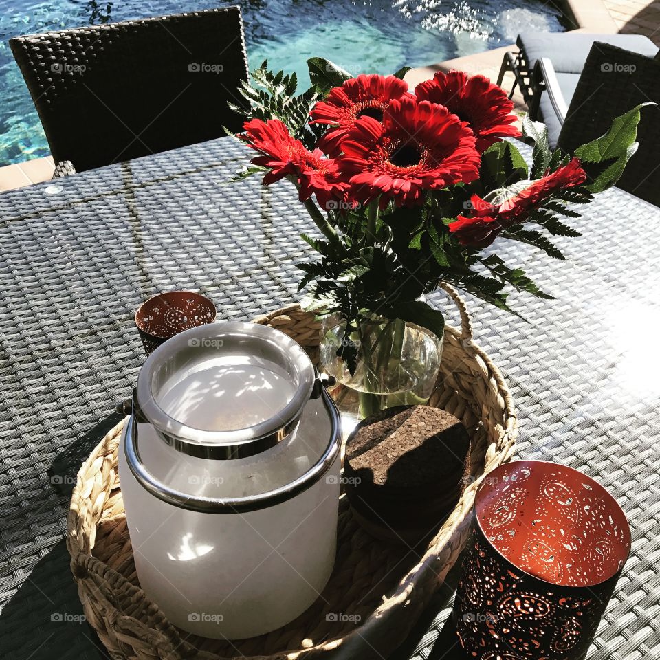 High angle view of jar and red flowers on table