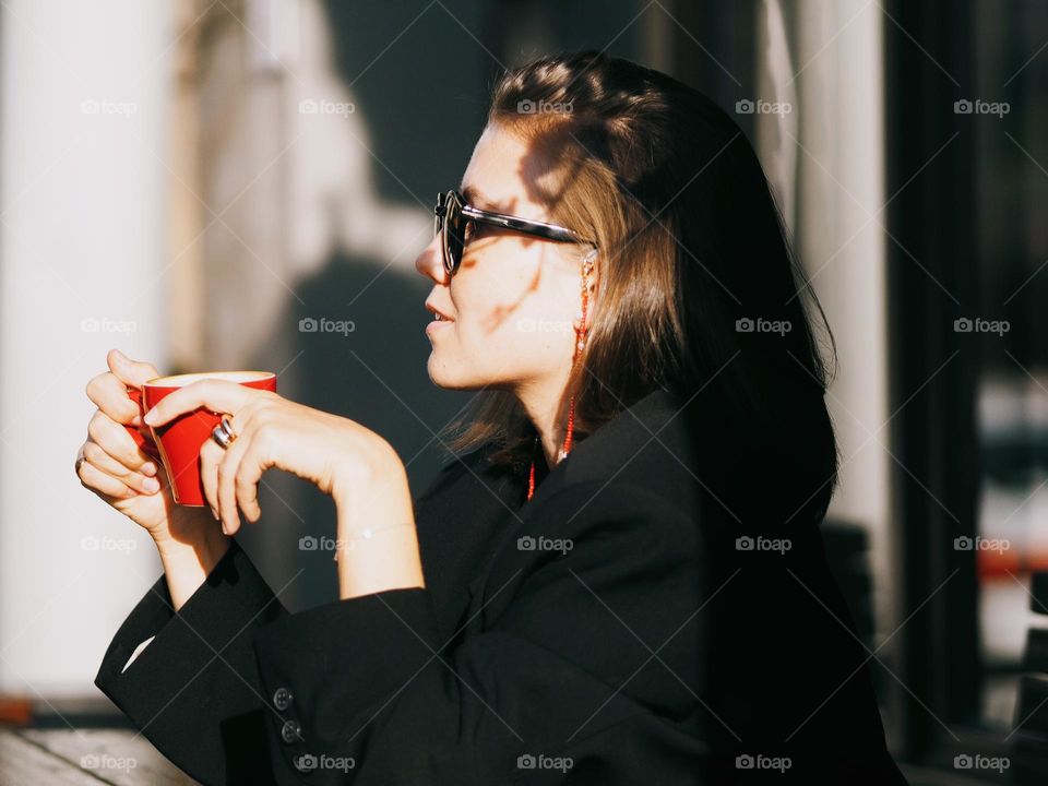 Young beautiful stylish girl drinking coffee or tea on a sunny summer day, portrait of woman 