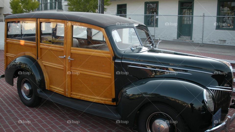 green and brown classic woody style vintage car cruising through the Monterey Peninsula in California