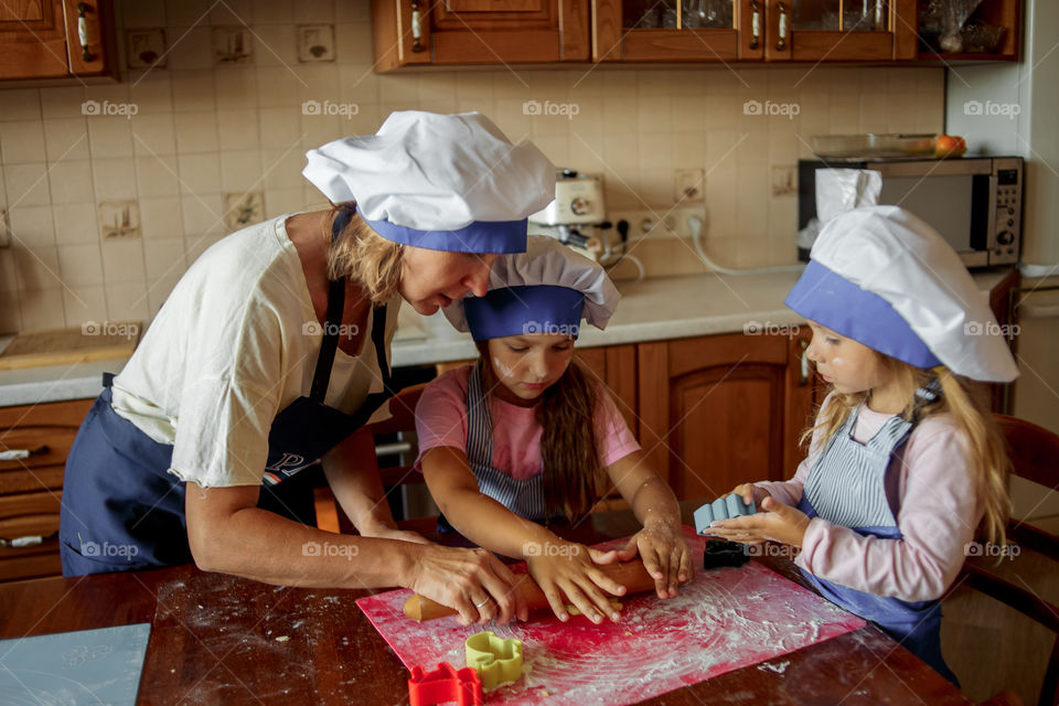 Little sisters with grandma cooking the biscuits 