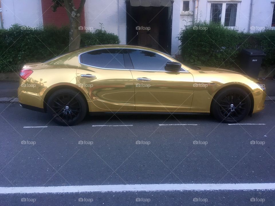 Side view of a gold Maserati Ghibli saloon car parked on Ravenscroft Avenue, Golders Green, London 